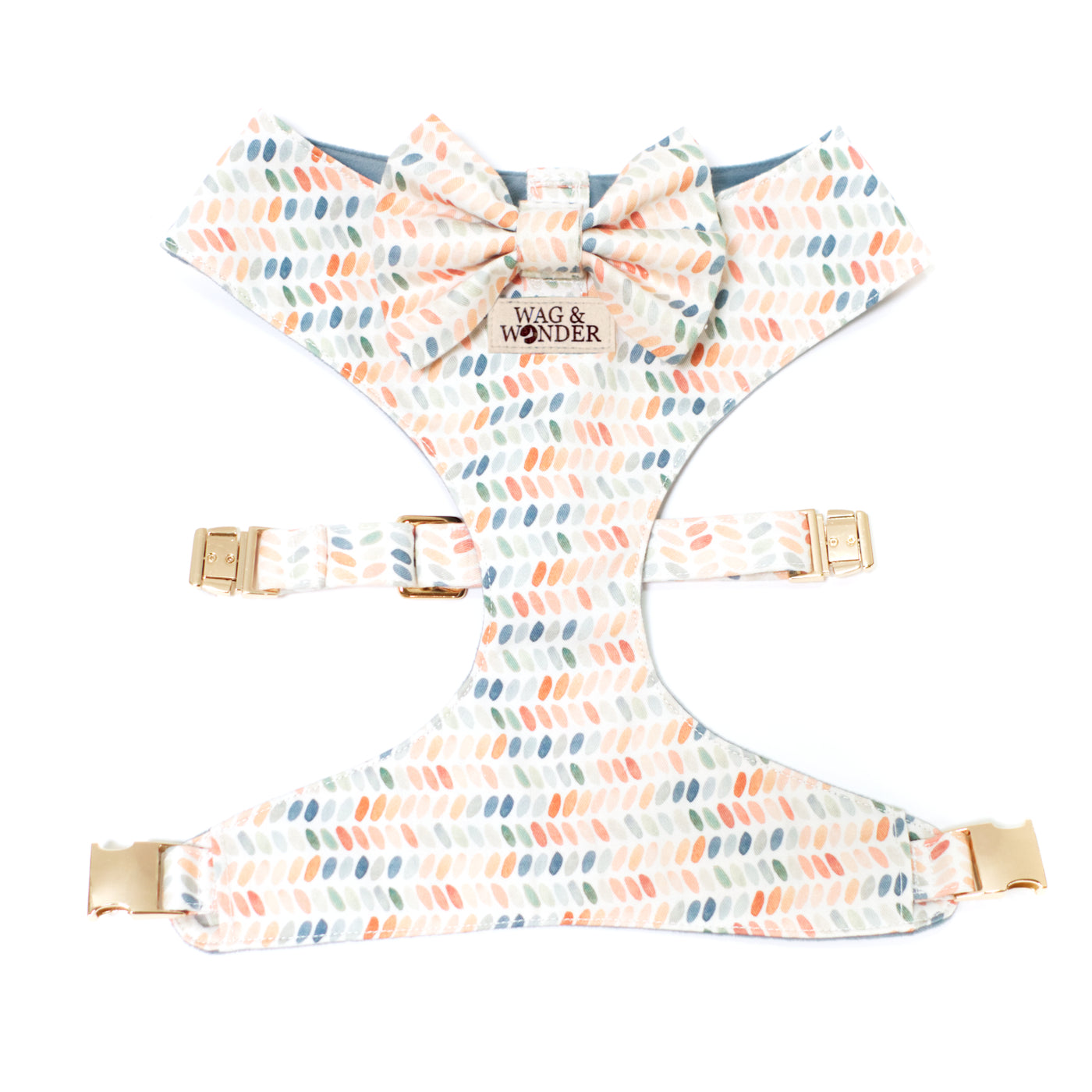 Reversible dog harness with bow tie in dusty blues, terra cotta, and sage greens in dot print.