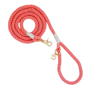 Rope dog leash arranged in coil with gold hardware in coral