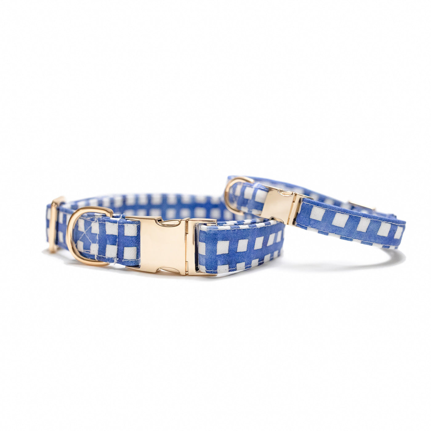 Two stacked dog collars with gold hardware in navy watercolor plaid