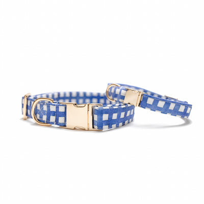 Two stacked dog collars with gold hardware in navy watercolor plaid