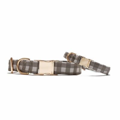 Two stacked dog collars with gold hardware in gray buffalo check