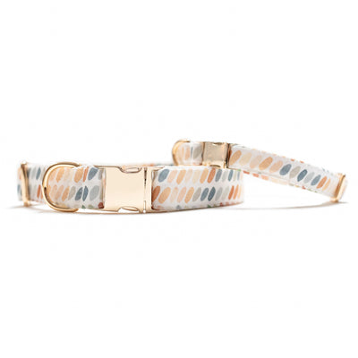 Two stacked dog collars with gold hardware in multi-color ovals