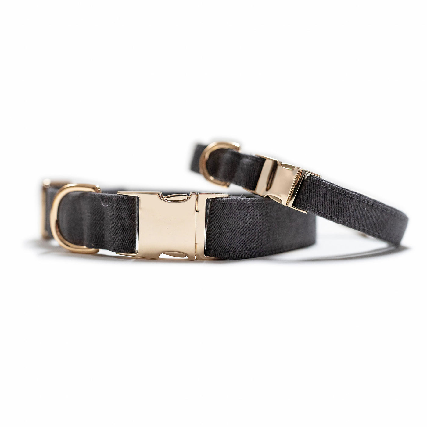 Two stacked dog collars with gold hardware in dark gray