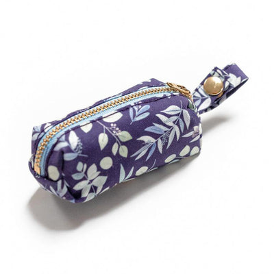 Side view of fabric rectangular pouch with zip closure and snap loop for poop bags in indigo background with multi-color foliage