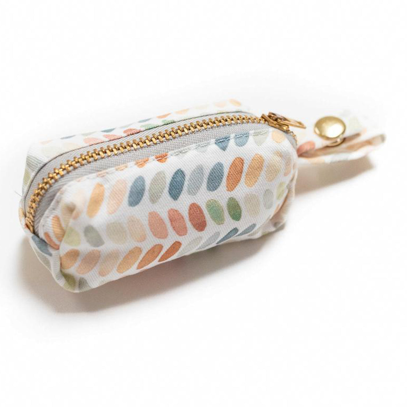 Side view of fabric rectangular pouch with zip closure and snap loop for poop bags in multi-color ovals